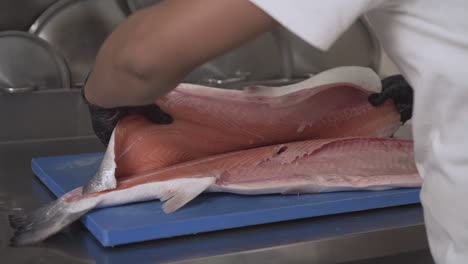 Primer-Plano-De-Un-Chef-Fileteando-Y-Volteando-Un-Salmón-Fresco