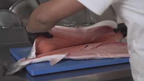 primer plano de un chef fileteando y volteando un salmón fresco