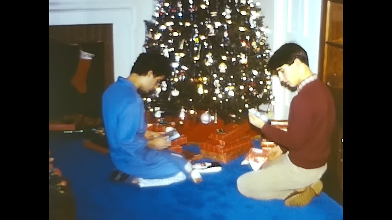 Two Men Sitting in Front of a Christmas Tree. CIRCA USA - 1970s: Two men from the 1970s, seated in front of a Christmas tree in the USA.