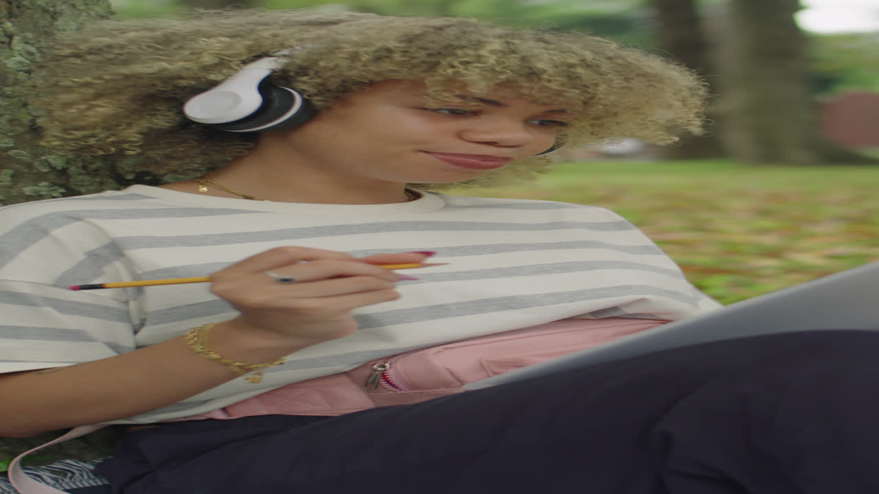 College Girl in Headphones Doing Homework in Park