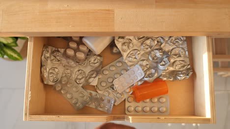 hand reaching into a messy drawer filled with medicine