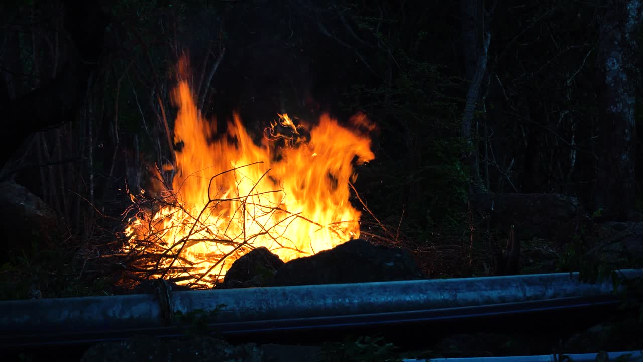 Scene with bonfire near road guard rail at twilight. Static