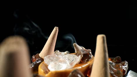 static shot of several unlit incense cones in a decorative rock garden