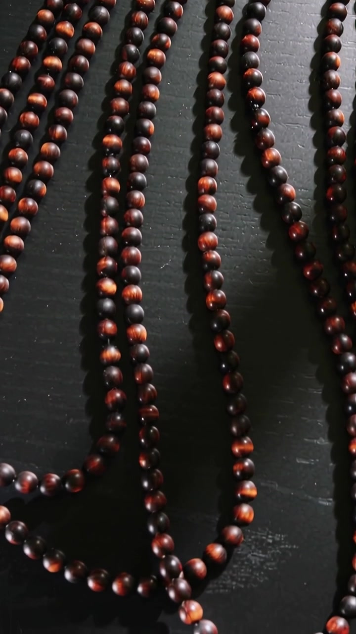 Vertical video: Shifting wooden beads sliding on dark tabletop, moving from tiny camera shake