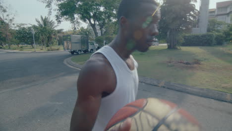 young black man dribbling basketball on the street