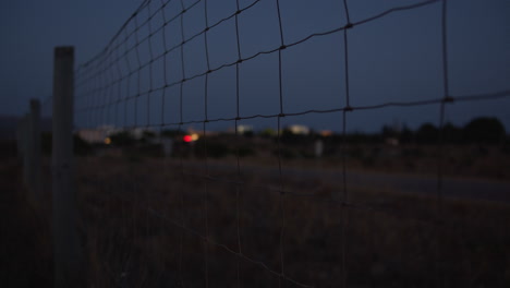 Vista-Nocturna-De-Un-Camino-Rural-A-Lo-Largo-De-La-Valla-Metálica-De-Alambre