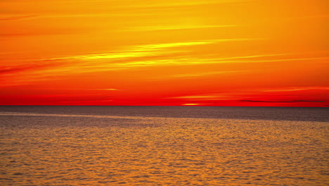 sunset on the ocean horizon with beautiful colors above the water in red, yellow, orange, timelapse, copy space