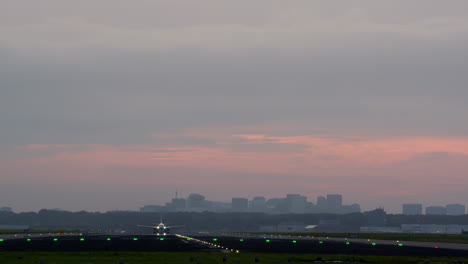 airplane landing at sunset with city skyline in background