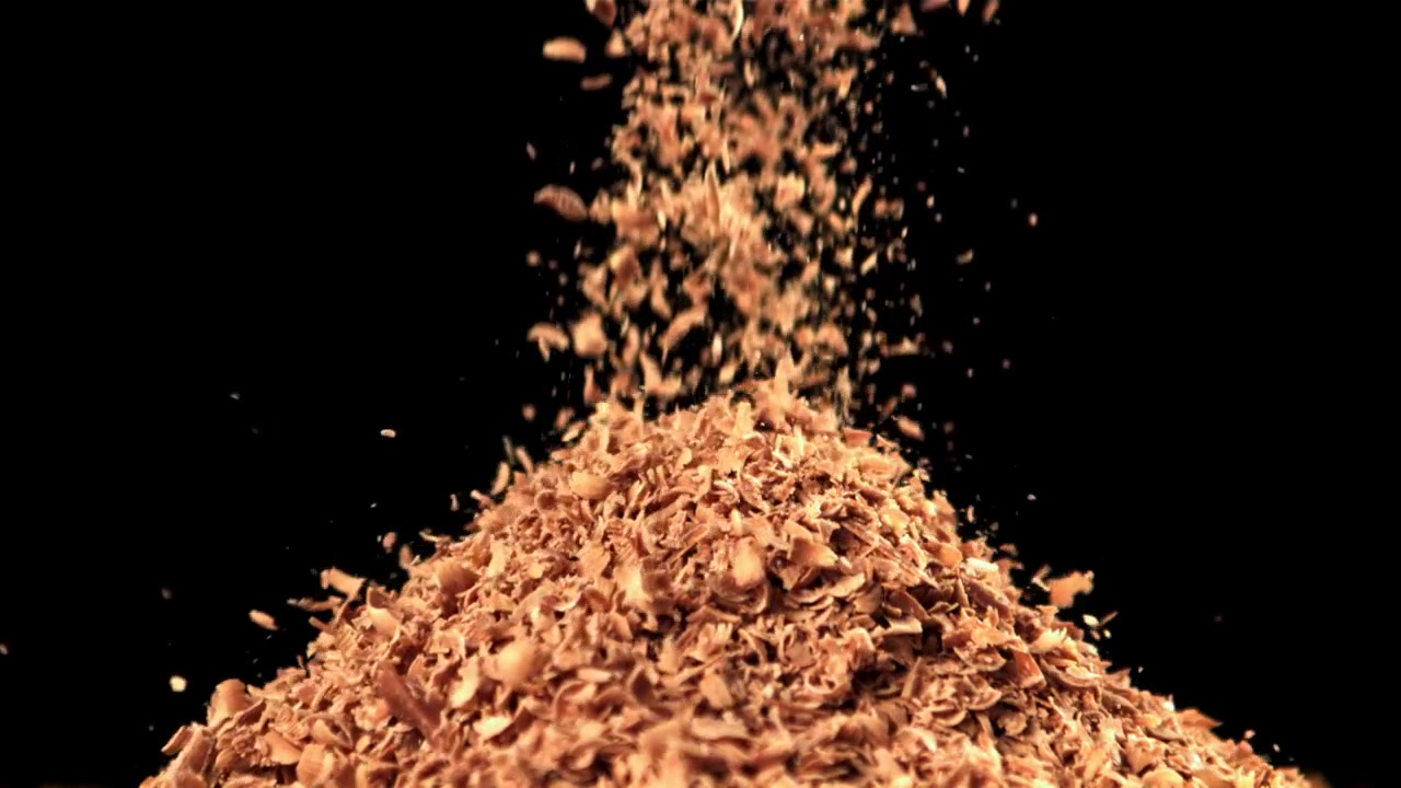 Trucioli di legno che cadono e si accumulano su sfondo nero
