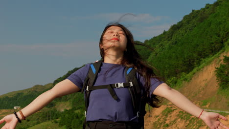 woman basking in the warm summer sun, smiling as wind blows through her hair