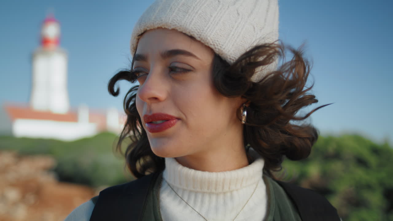 미소 짓는 관광객의 초상화가 흐릿한 등대 시야에서 포즈를 취하고 있습니다. 여행하는 행복한 소녀