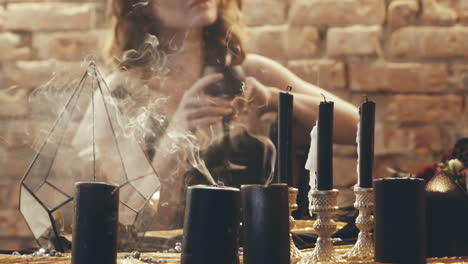 Witch woman holding candle. Close up of woman in a witch suit on ritual with candle in room