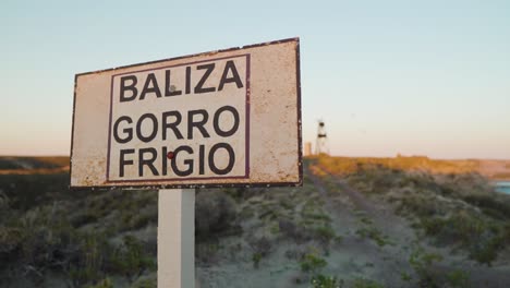 Aufschlussreicher-Schuss-Des-Phrygischen-Kappenleuchtfeuers-Hinter-Der-Baliza-Gorro-Frigio-beschilderung-In-Puerto-Madryn,-Chubut,-Argentinien---Zeitlupe