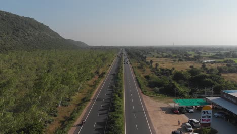 Flying-over-the-center-line-of-a-highway-in-India-with-a-cozy-pitstop-café-beside-the-road