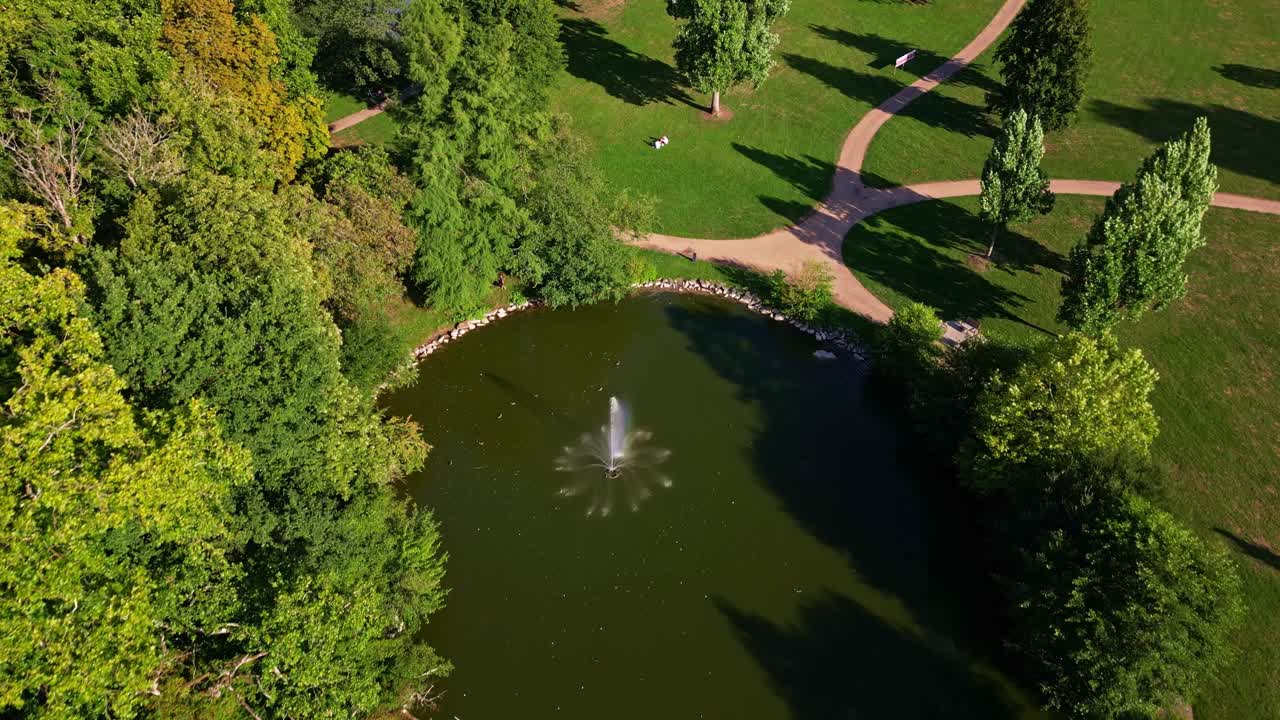 Tilt down drone movement over The Ondine Park aka Le Parc des Ondines' pond with water fountain in the middle, Changé, Mayenne, France