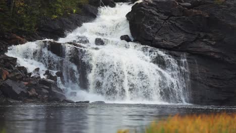 A-waterfall-cascades-over-the-dark-cliffs-and-is-reflected-on-the-surface-of-the-lake