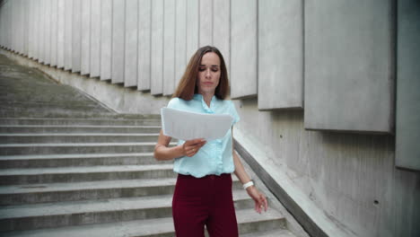 Attractive-businesswoman-holding-business-papers.-Busy-woman-running-downstairs