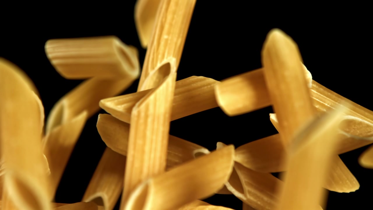 Pasta Penne Cruda che Cade al Rallentatore su Sfondo Nero