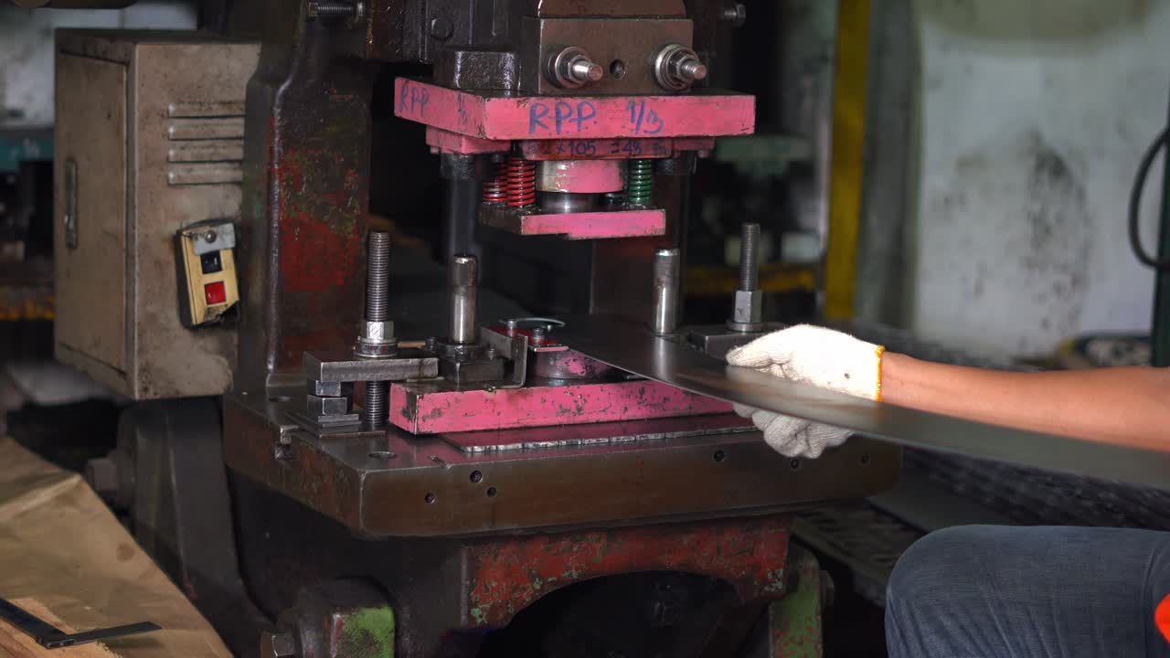 la máquina está trabajando estampando un círculo de una larga placa de acero, controlada por el trabajador.