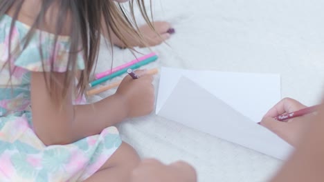 a mother and her young daughter sit on a blanket in the backyard, engaging in a drawing activity together. the outdoor scene captures a peaceful family moment, fostering creativity and bonding.