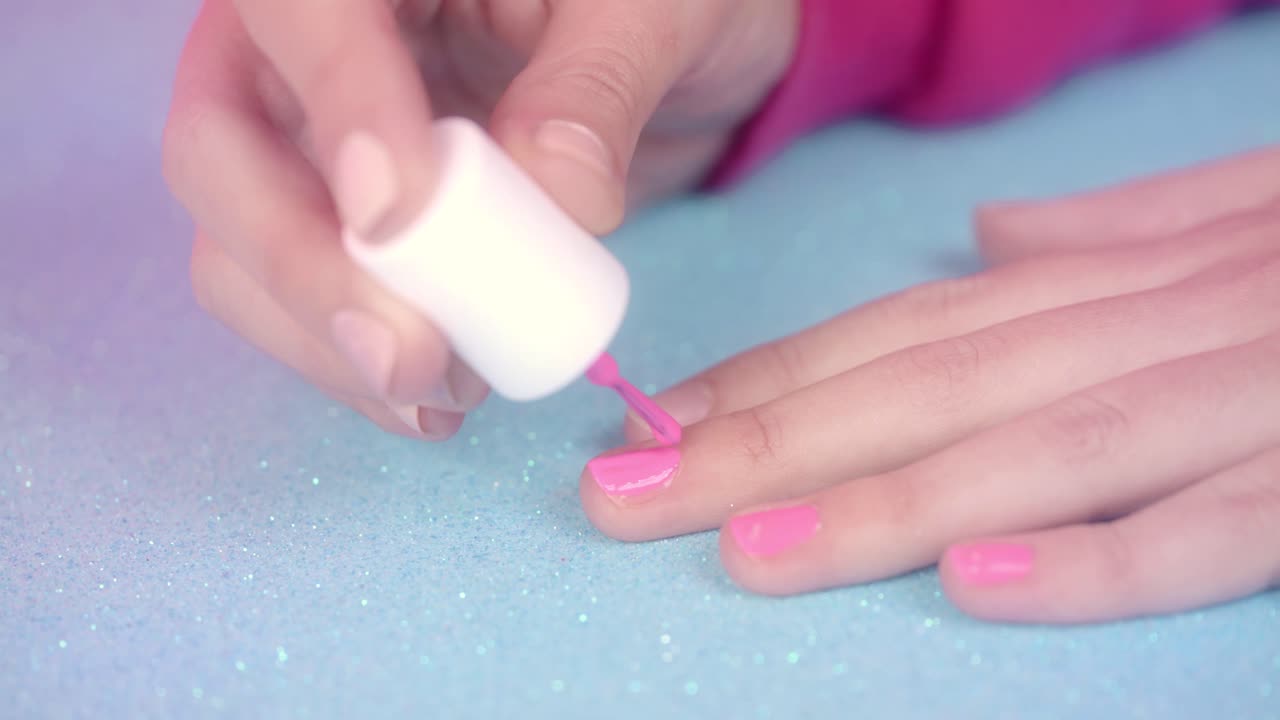 Nærbillede af hænder, der påfører pink neglelak