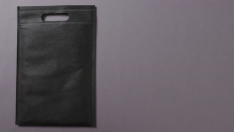 close up of black bag on grey background, copy space, slow motion