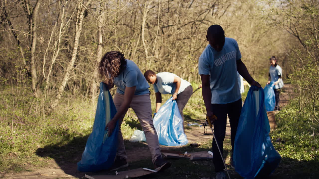 Diverse men volunteers pick up rubbish and plastic trash with tongs