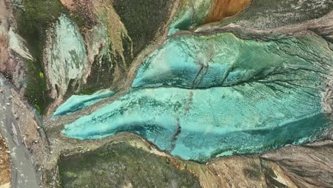 aerial drone azimuthal movement to the right at medium altitude, revealing the entirety of grænihryggur, the green rock, in landmannalaugar, iceland, emphasizing the medium tones of orange and green