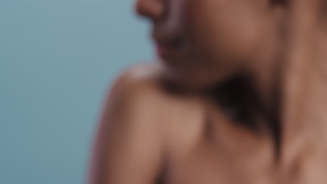 close up beauty portrait attractive african american woman feathers falling on smooth skin touching bare shoulders enjoying natural skincare gently caressing body in blue background slow motion