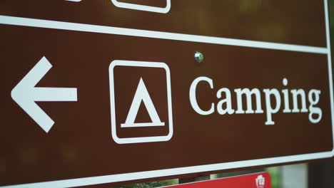 close up view of black color camping road sign indicating the the direction of the camp site