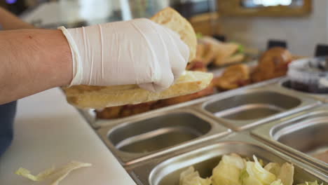 nahaufnahme der hände eines mannes, der kohl anrichtet und sandwiches macht