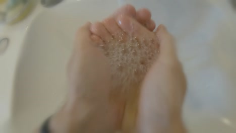 pov washing face in the morning in a white sink first person perspective