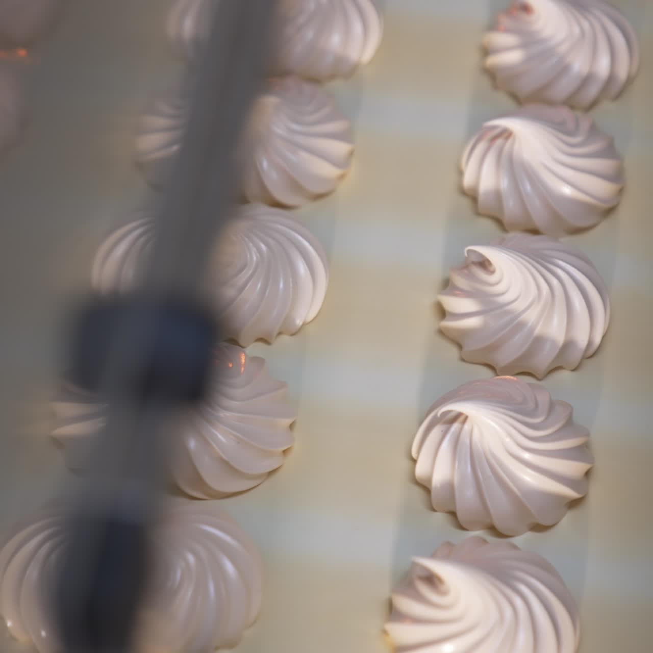 Delicious creamy marshmallow sweets moving slowly on the conveyor belt. Freshly-made vanilla desserts come out from machine. Close up. Top view