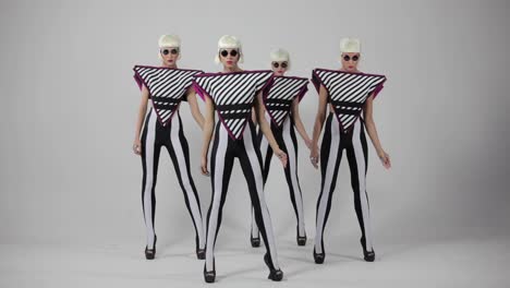 stylish women in futuristic costumes dancing