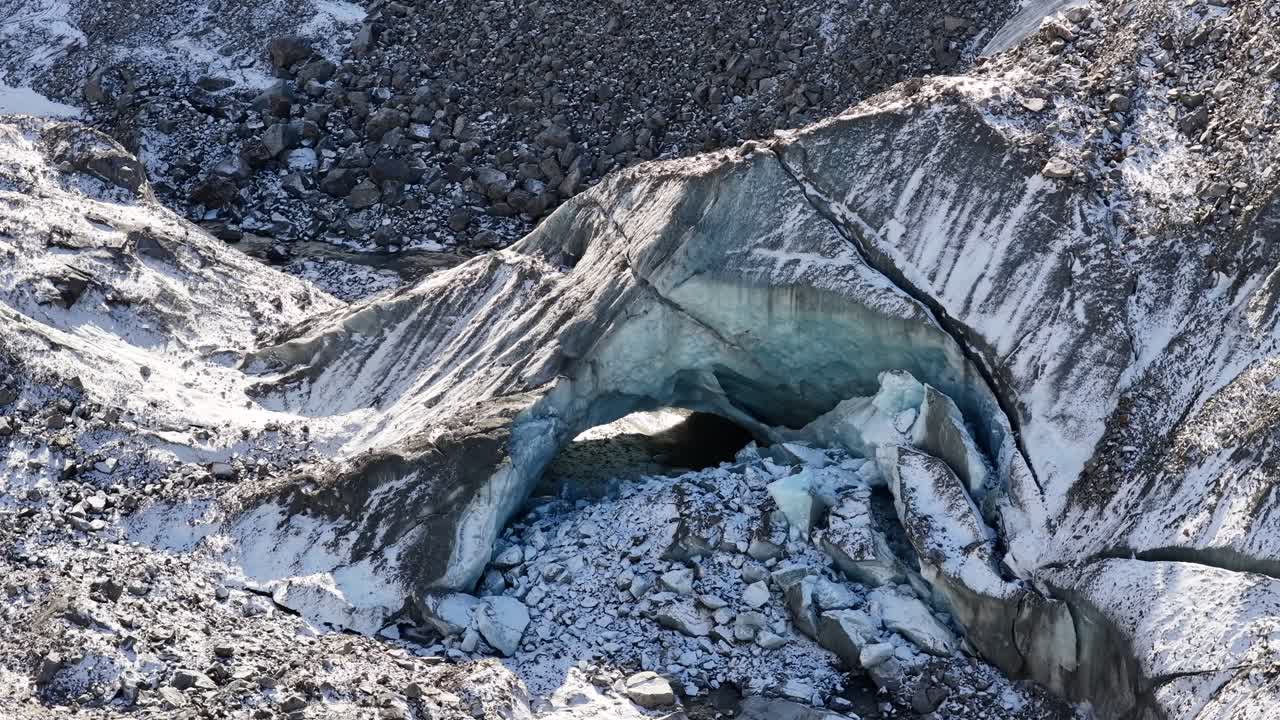 Drone flying over snowy alpine glacier with rugged mountains and cold blue light in the Engadin valley, Switzerland