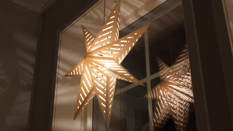 decorative advent star hangs by window at night, slow pan from below