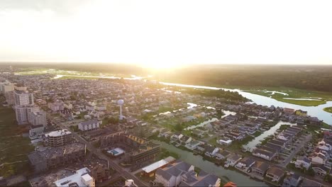 Rotating-drone-shot-flying-away-from-ocean-towards-sun-at-sunset