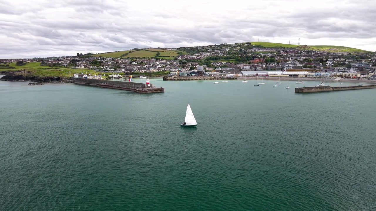 Vista aerea epica di un piccolo yacht che entra nel porto di Wicklow in una giornata di sole, Irlanda. Marino, costiero.