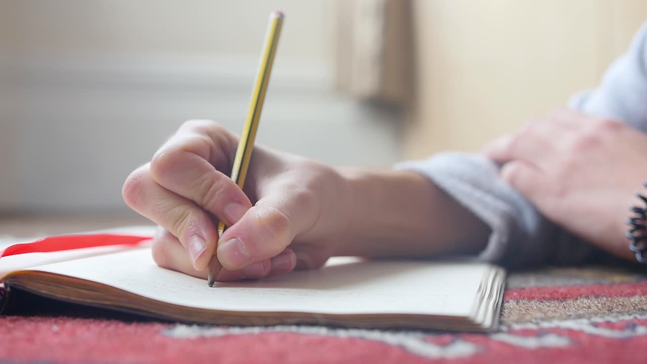 vista del piso de una persona tendida en la alfombra de la sala de estar mientras escribe en cámara lenta durante el día