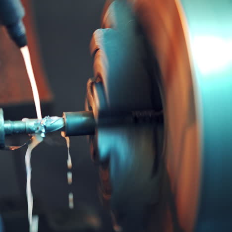 a lathe processes the metal workpiece with coolant which cool the tool and increase the productivity of the process. close-up. blurred background.