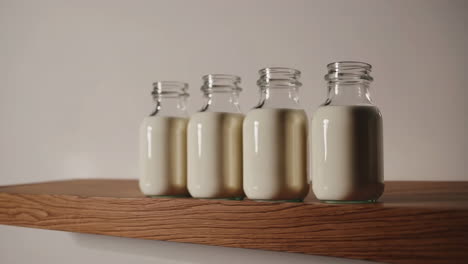 Four Bottles of Milk on a Wooden Shelf
