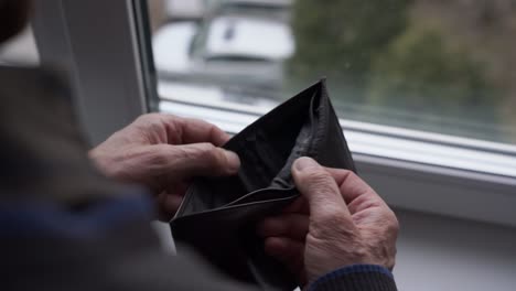 retired elderly person open and close old empty wallet