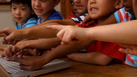 cute pupils using laptop in classroom