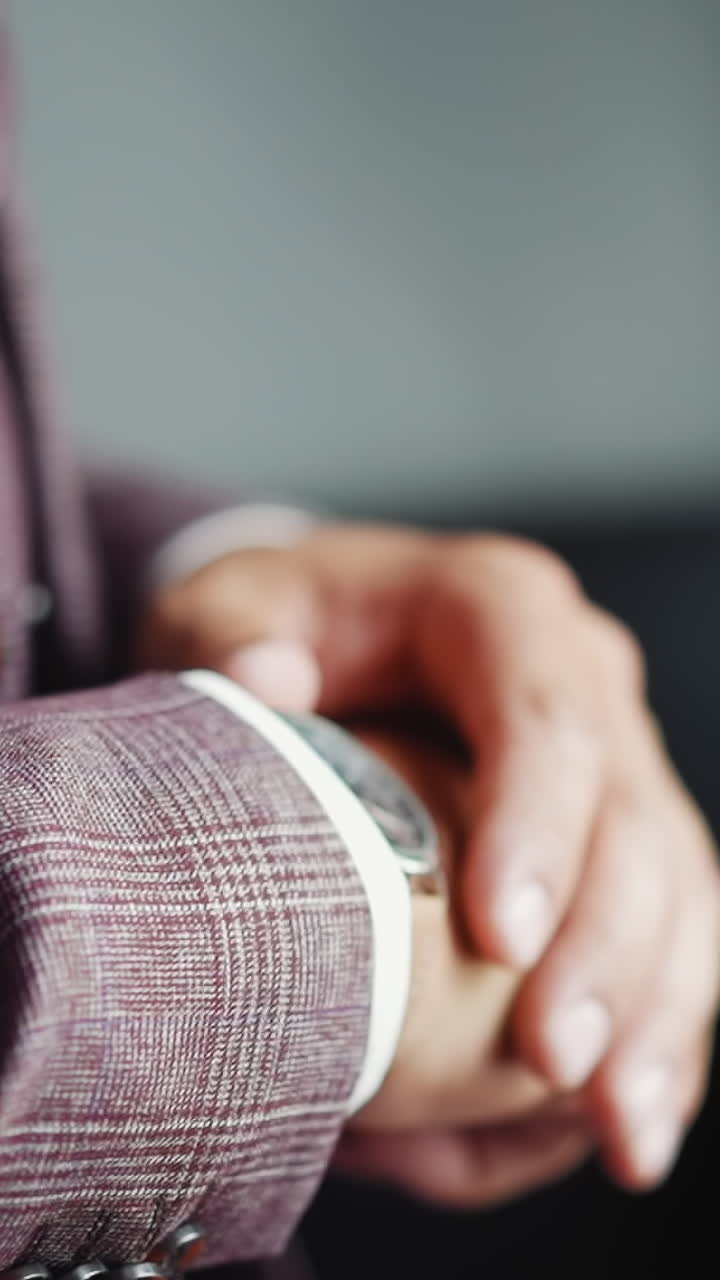 Businessman in elegant grey suit checks up time looking at expensive wristwatch in office closeup slow motion. Hurrying up man at workplace. Corporate life