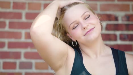 girl smiling runs her hands through her hair and pulls it over one shoulder