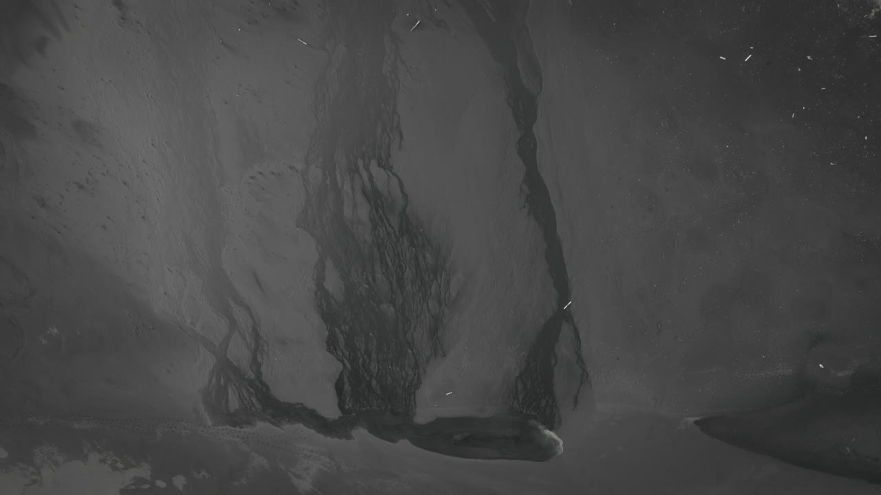 arriba abajo playa de arena negra aérea, río que desemboca en el mar, olas que se estrellan contra la arena volcánica, islandia