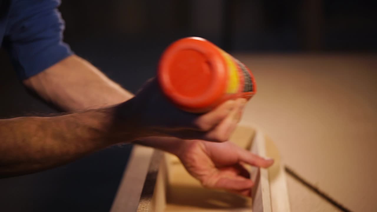 primer plano de una persona usando una pistola de pegamento para montar paneles de madera.