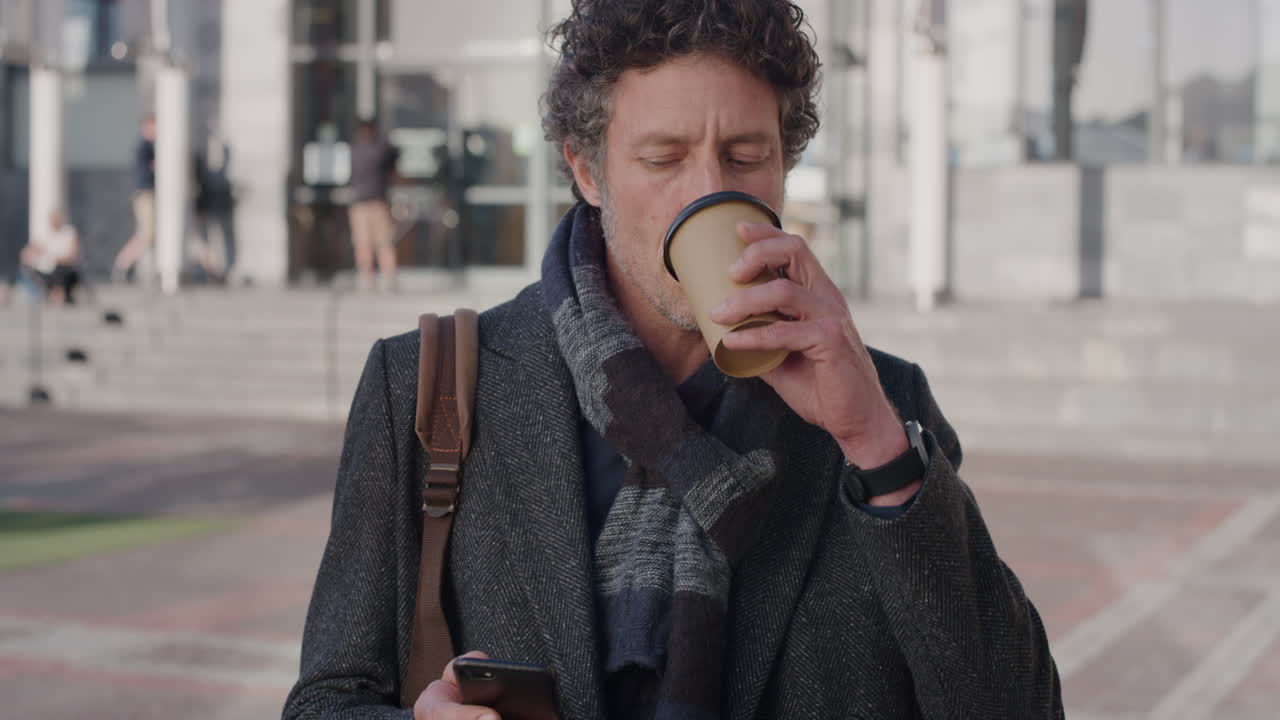 retrato de un hombre de negocios maduro feliz usando un teléfono inteligente bebiendo café disfrutando de los mensajes de texto navegando por los mensajes en línea en el teléfono móvil en la ciudad en cámara lenta