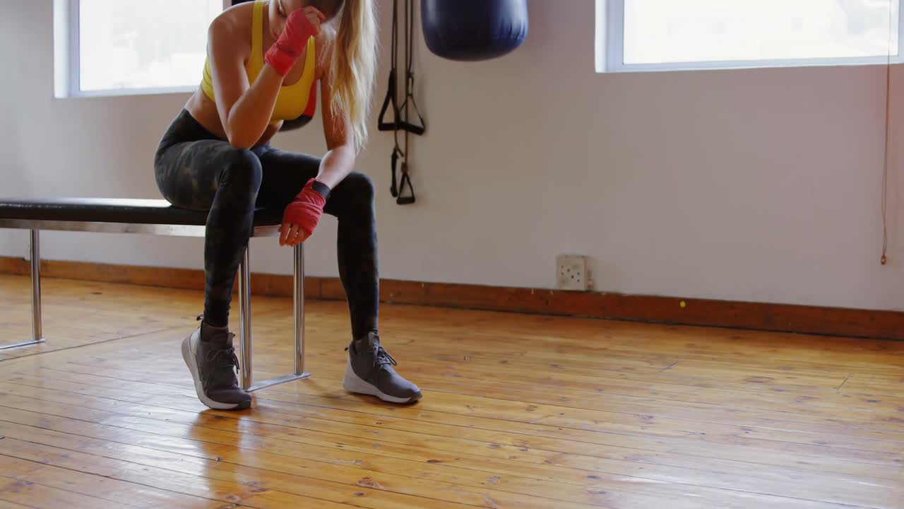 Female boxer relaxing in fitness studio 4k