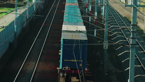 A-slow-freight-train-powered-by-electricity-making-its-way-through-a-rural-area-in-Austria-while-being-overtaken-by-a-fast-passenger-train